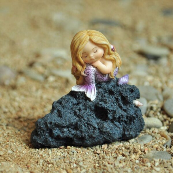 Lille tankefuld havfrue på klippe